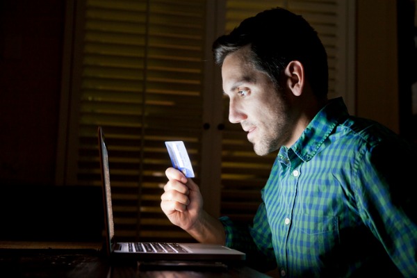 Man looking at computer screen and holding debit card